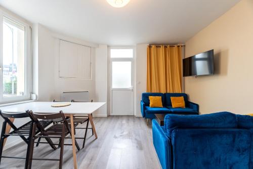 un salon avec une table et un canapé bleu dans l'établissement Maison 4 ch, idéal déplacement pro, parking, rénové, à Rouen