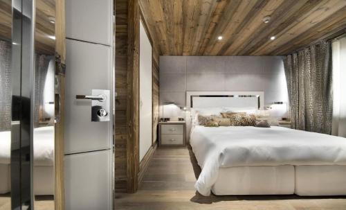 a bedroom with a large white bed and a wooden ceiling at Résidence Eden - Chalets pour 10 Personnes 754 in Courchevel
