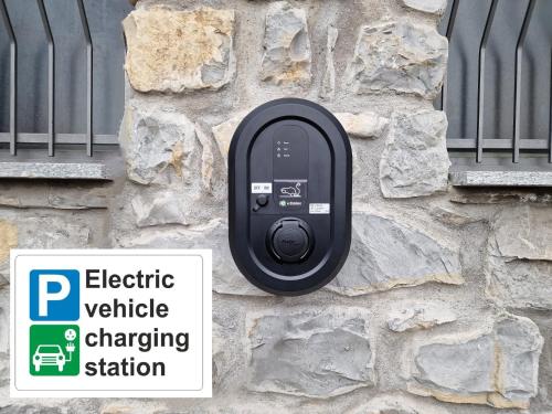 a black electric vehicle charging station attached to a stone wall at Hotel Montegrino in Montegrino Valtravaglia