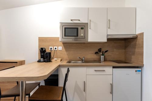 une cuisine avec des armoires blanches et une table avec un micro-ondes dans l'établissement Studio cosy, idéal déplacement pro, rénové, à Rouen