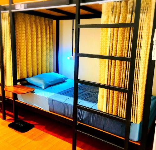Three Hostel at Night Market Pakchong في Ban Sao Thong: غرفة نوم مع سرير بطابقين مع سلم