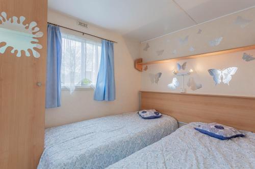 two beds in a bedroom with butterflies on the wall at Mobilhome au vert in Roquebrune-sur-Argens