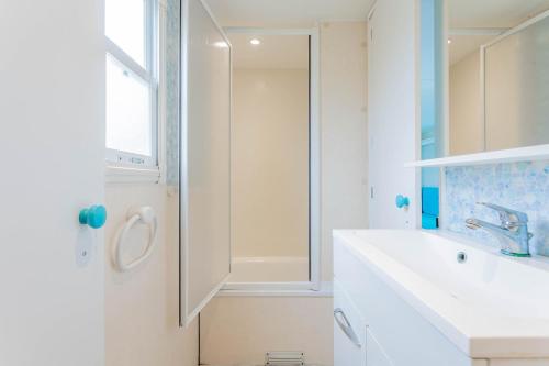 a white bathroom with a sink and a shower at Mobilhome au vert in Roquebrune-sur-Argens