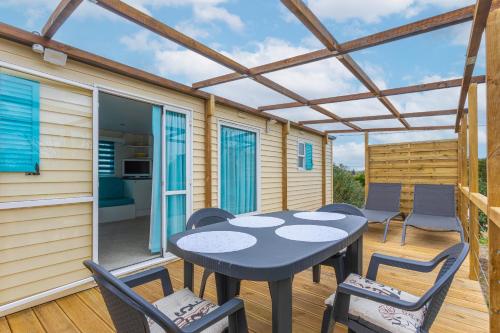 un patio avec une table et des chaises sur une terrasse dans l'établissement Mobilhome au vert, à Roquebrune-sur Argens