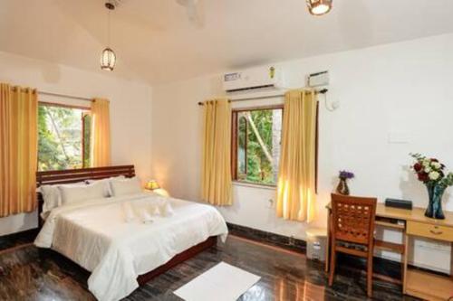 um quarto com uma cama, uma secretária e 2 janelas em Casa Verde · Luxurious 3BHK Villa in Goa Velha em Goa