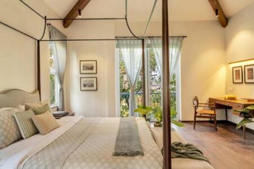 a bedroom with a large bed and a desk at La Margarida · Super luxury 5BHK villa in Anjuna in Goa