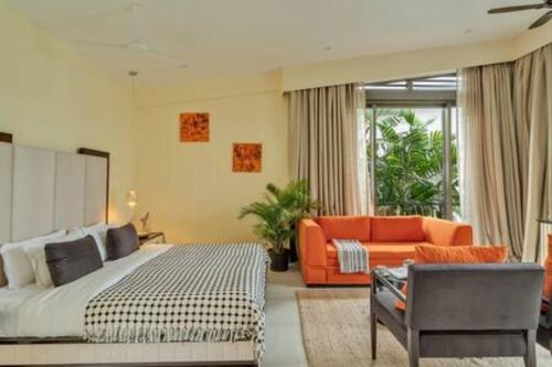 a bedroom with a bed and an orange couch at sohonos · Luxurious 3bhk villa in Candolim in Goa