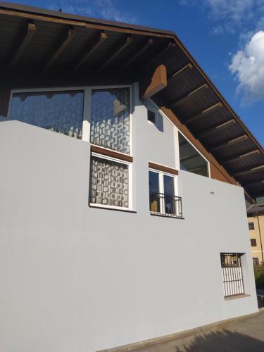 Casa blanca con techo negro y ventanas en B&B Seventy Design, en Dimaro
