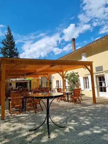 a wooden pavilion with a table and chairs in front of a building at Manoir Belle Fontaine in Noaillan