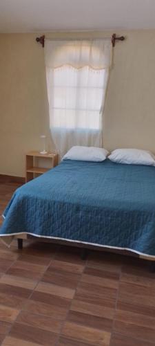um quarto com uma cama com um cobertor azul e uma janela em The Hostal Elohim em Panajachel