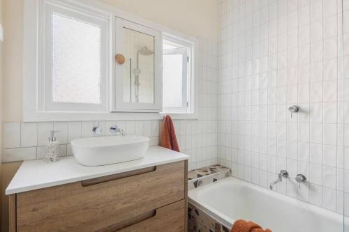 a white bathroom with a sink and a tub at Hazel House Ballarat in Wendouree