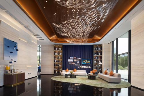 a hotel lobby with a chandelier on the ceiling at Hampton by Hilton Dongguan Liaobu Songshan Lake Avenue in Liao-pu