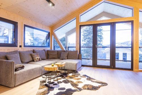 a living room with a couch and large windows at Naturchalets Turracher Höhe by ALPS RESORTS in Turracher Hohe