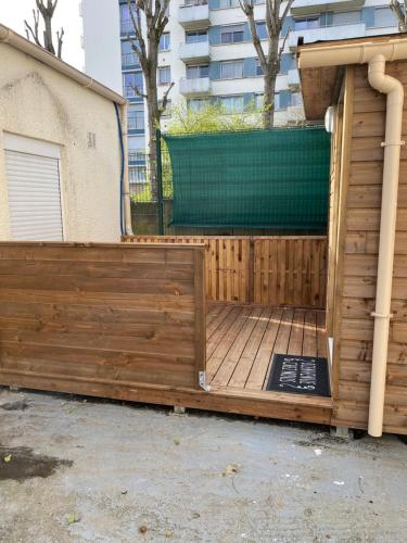 une terrasse en bois avec une porte en face d'un bâtiment dans l'établissement Petit chalet, à Aubervilliers