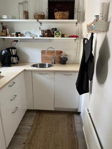 een keuken met witte kasten, een wastafel en een tapijt bij Hangon helmi pariskunnalle tai yksin matkustavalle in Hanko