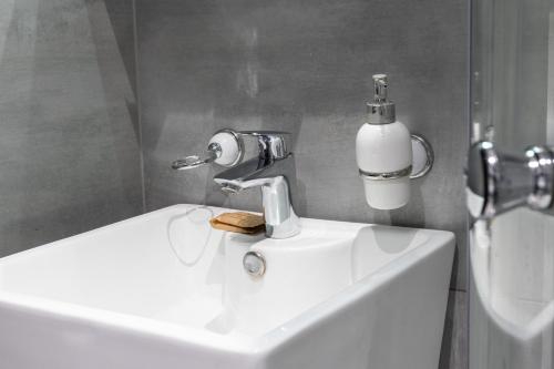- un lavabo dans la salle de bains avec un distributeur de savon dans l'établissement Starowiślna 36 Apartment with Mezzanine, à Cracovie