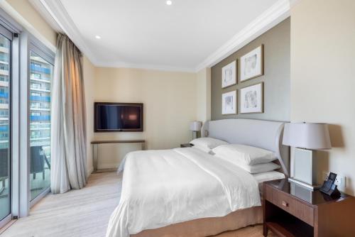a bedroom with a white bed and a tv at The Address Fountain Views - Residence 2 Bedroom with Burj Khalifa view in Dubai