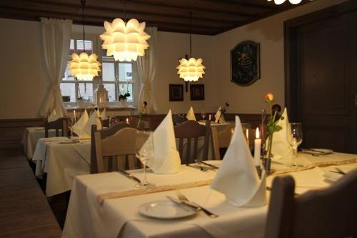 ein Esszimmer mit weißen Tischen und Kronleuchtern in der Unterkunft Hotel und Gasthof Zur Laute in Mindelheim
