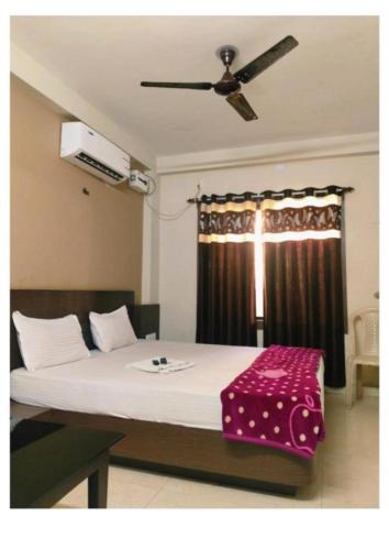 a bedroom with a large bed with a ceiling fan at Hotel UK Palace Puri Near Sea Beach Best Seller in Puri