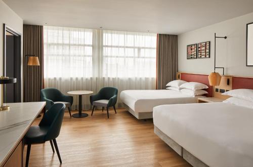 a hotel room with two beds and a table and chairs at Manchester Marriott Hotel Piccadilly in Manchester