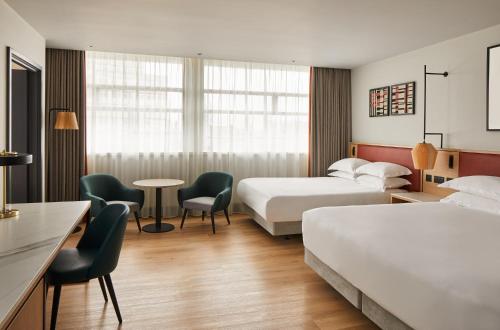 ein Hotelzimmer mit 2 Betten, einem Tisch und Stühlen in der Unterkunft Manchester Marriott Hotel Piccadilly in Manchester