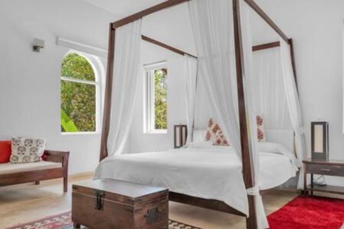 a bedroom with a canopy bed with a trunk at Villa Divina · Luxurious 4BHK Villa in Candolim in Goa