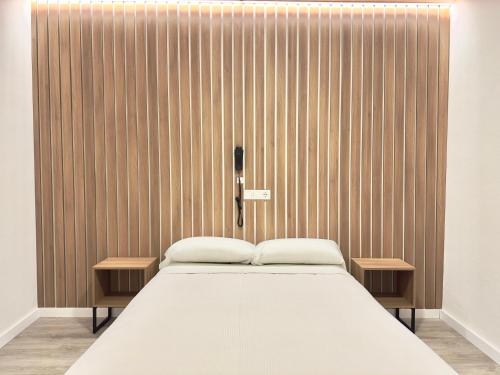 a bed in a room with a wooden wall at Hotel Victoria Centro in Almuñécar