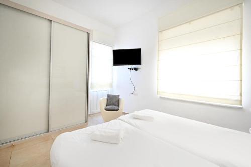 a white bedroom with a bed and a chair at Chic 2BR Apartment close to the beach by HolyGuest in Tel Aviv