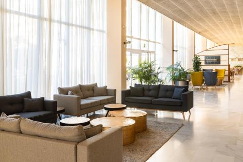 a living room with couches and tables and windows at htop Platja Park #htopFun in Platja  d'Aro
