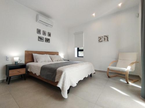 a white bedroom with a bed and a chair at Silver Cozy Getaway - 3 Pearls Pool Retreat in Dhémbla