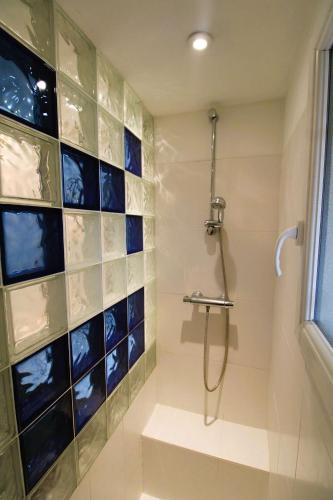 La salle de bains est pourvue d'une douche avec du carrelage bleu sur le mur. dans l'établissement Gasdu - Golfe de St-Tropez- Appartement avec accès mer, à Gassin