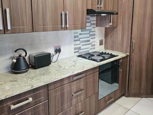 a kitchen with a stove and a tea kettle on the counter at Grand Diamond Lodge in Roodepoort
