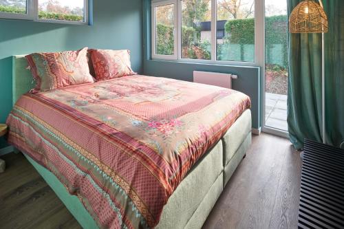 ein Schlafzimmer mit einem Bett mit einer Decke und Fenstern in der Unterkunft Lacuna VITA in Lanaken