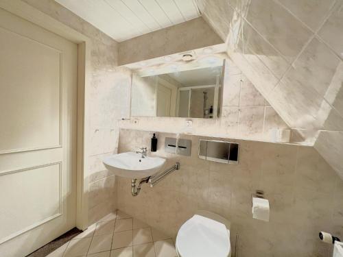 a white bathroom with a toilet and a sink at Groegers Ferienzimmer in Hohwacht