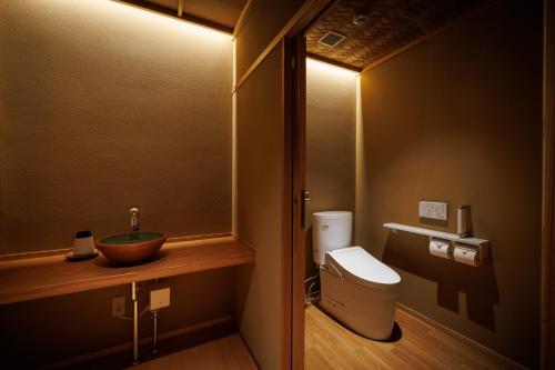 a bathroom with a sink and a toilet with a mirror at Shoraiso in Yamanouchi