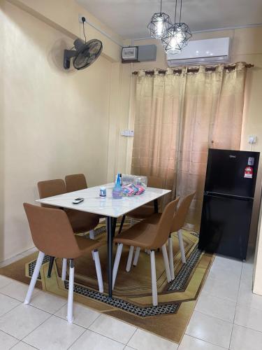 una sala da pranzo con tavolo e sedie bianchi di B&K Homestay Lahad Datu a Lahad Datu