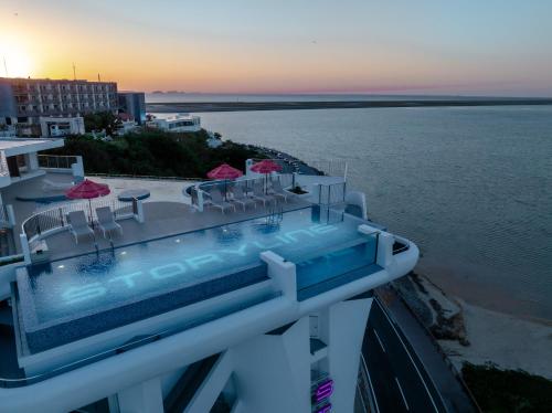 a pool with chairs and umbrellas next to the water at THE SENAGAJIMA STORYLINE in Tomigusuku