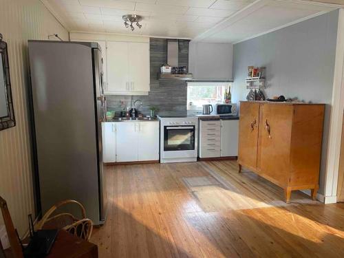 uma cozinha com armários brancos e um frigorífico preto em In the nature em Boden
