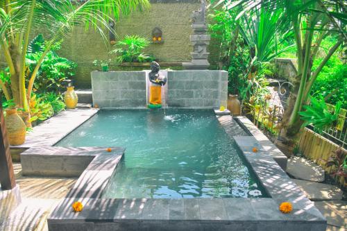 a pool of water with a fountain in a garden at Ume Sita Villa and Homestay in Ubud
