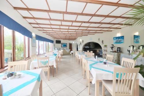 a dining room with white tables and chairs at Mermaid Guest House in Struisbaai