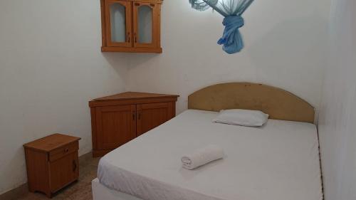 a bedroom with a white bed and wooden cabinets at Tharindu Hostel in Dankotuwa