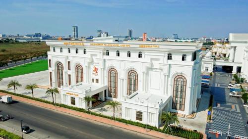 THE PREMIER PALACE HOTEL AND SPA في بنوم بنه: عمارة بيضاء فيها نخل قدام شارع