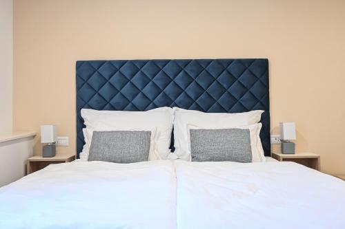 a large bed with a blue headboard and two pillows at Šangulin Palace V in Biograd na Moru