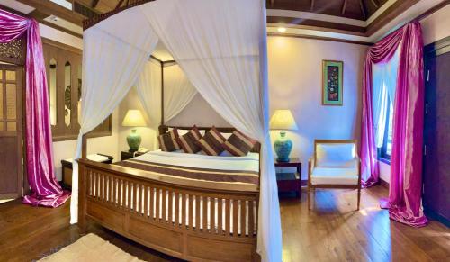 a bedroom with a canopy bed with pink curtains at Amata Lanna Village อมตะล้านนาวิลเลจ in Chiang Mai