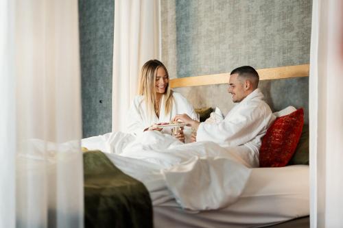 Ein Mann und eine Frau sitzen im Bett in der Unterkunft Hotel Verviers Van der Valk in Verviers
