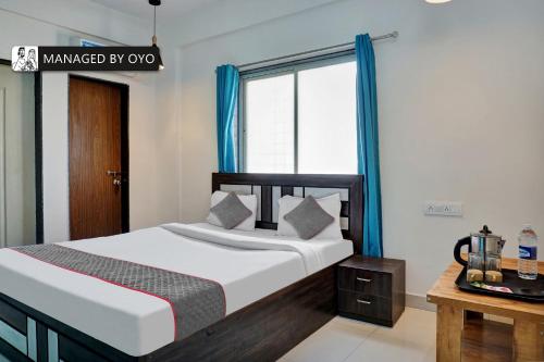 a bedroom with a bed with blue curtains and a window at Townhouse Imperial Inn Hinjewadi in Hinjewadi