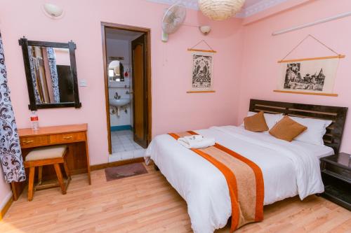 a bedroom with a bed and a desk and a mirror at Cloud 9 Garden in Kathmandu