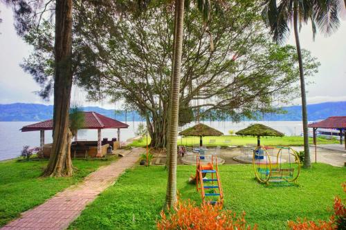 a park with a playground with a slide and trees at Hotel Pandu Lakeside Tuktuk in Tuktuk Siadong