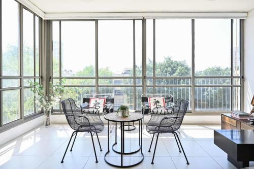 a room with a table and chairs and windows at Smiling Joe by HolyGuest in Tel Aviv