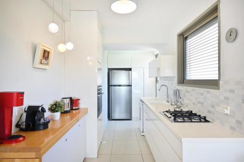 a kitchen with white counters and a stainless steel refrigerator at Smiling Joe by HolyGuest in Tel Aviv